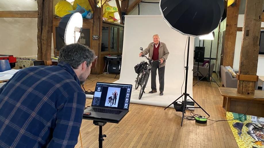 A man on a bicycle is being photographed by a photographer