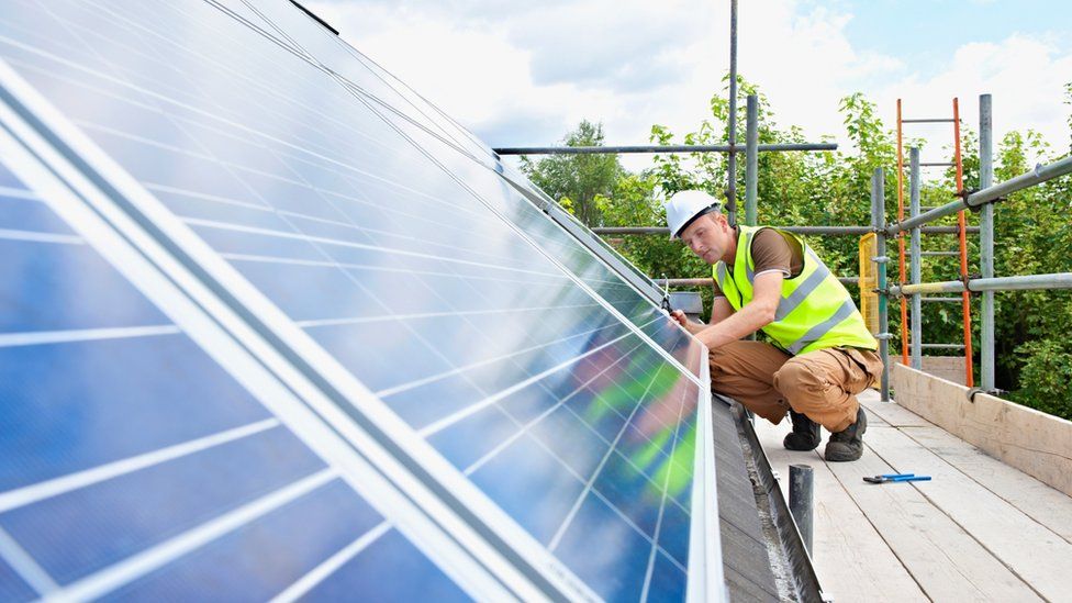 A man fitting solar power panels to a roof