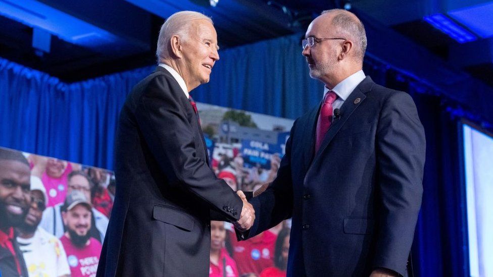 Joe Biden and Shawn Fain shake hands