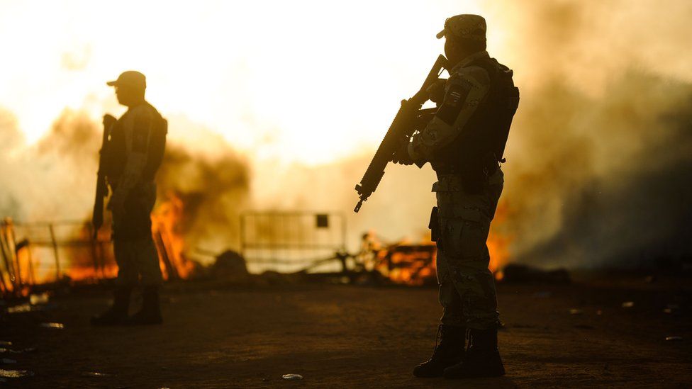 Police stand near barricades set on fire by protesting prison inmates in Natal, Rio Grande do Norte, Brazil