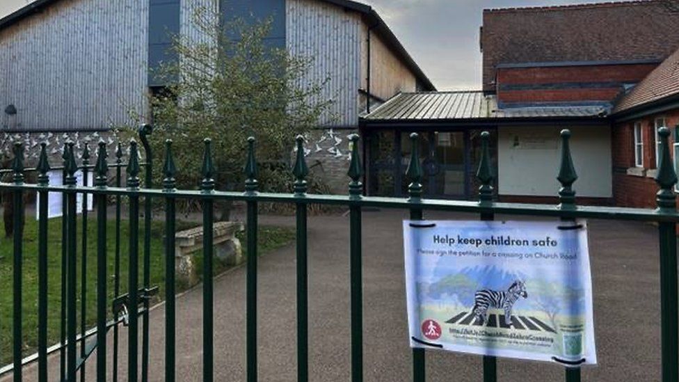 Image of a poster advertising the petition hung on a gate at the school