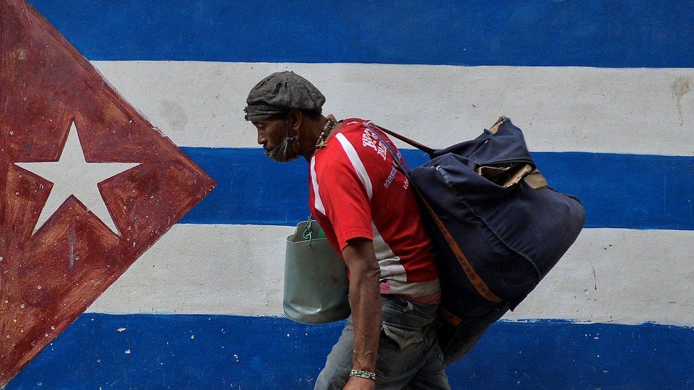 A man walks next to a graffiti of the Cuban flag in Havana