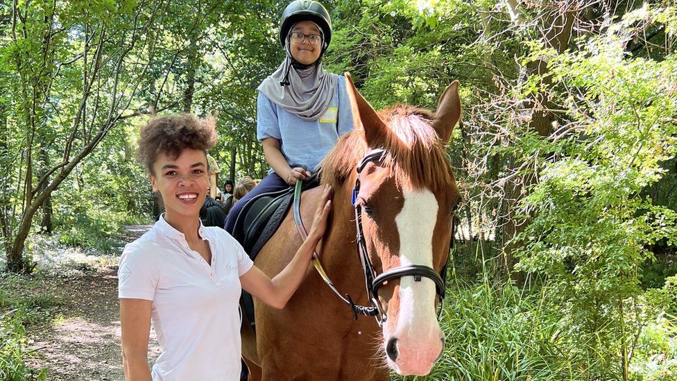 Young girl on a horse, with a woman stood beside them