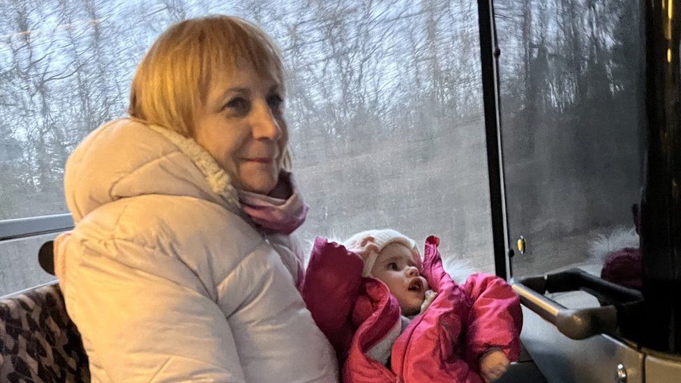 A carer holds a child on a bus travelling to the Polish border