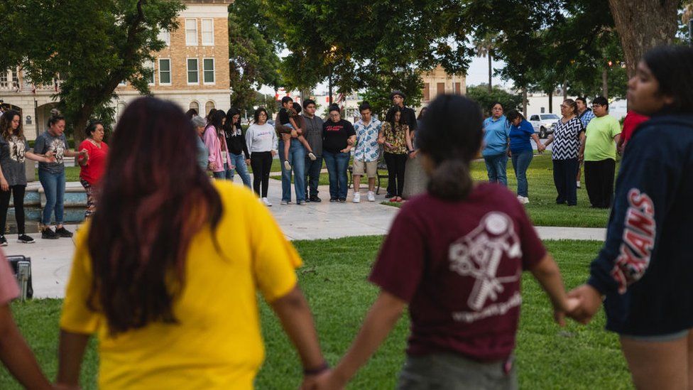 People hold hands at a vigil in Uvalde