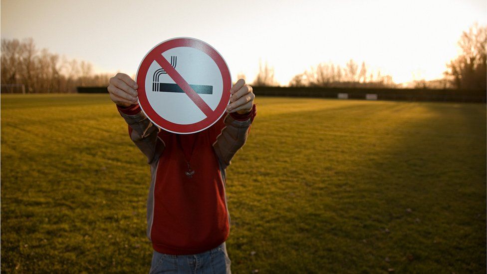A child holding up a no smoking sign