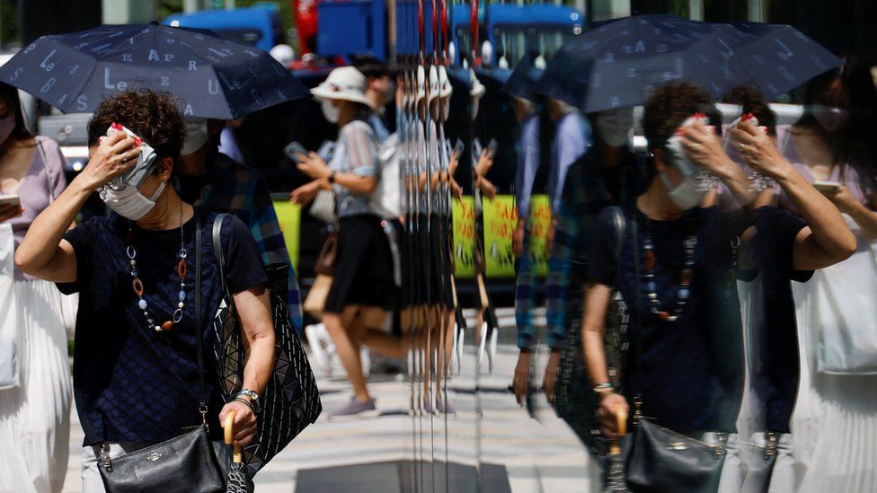 A woman wipes her face as she walks on a street in Tokyo