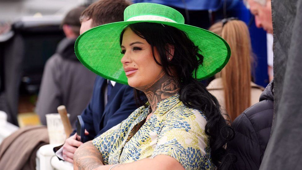 Woman in green hat watching racing at Aintree Ladies Day 2024