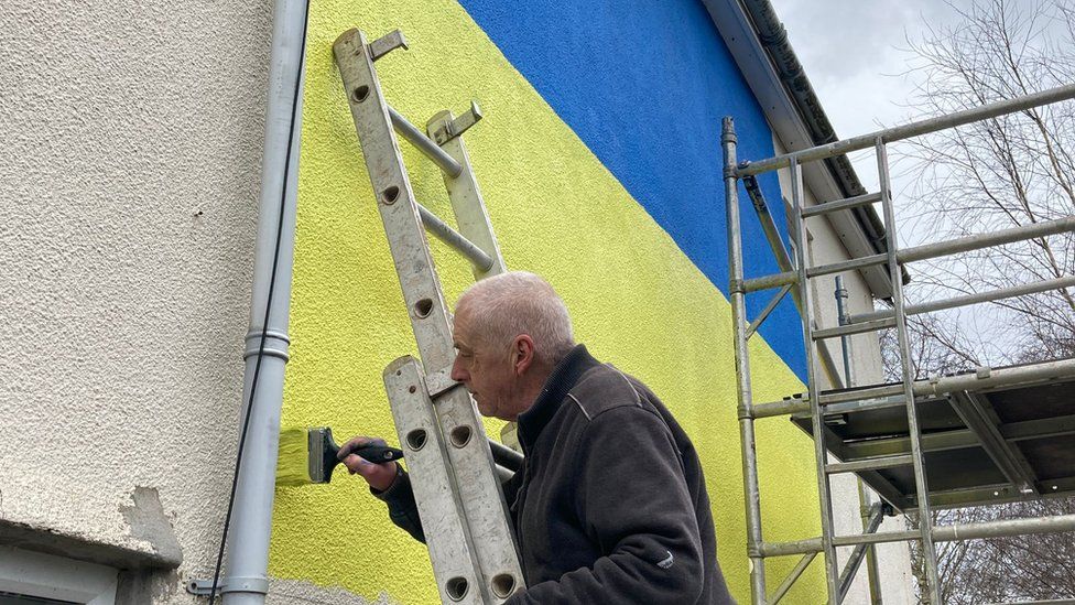 Ukranian flag being painted on a wall