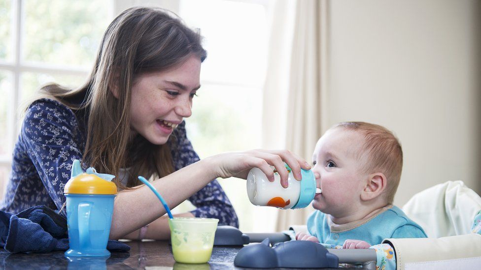 Girl feeding a baby