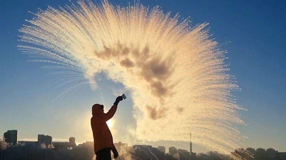 A man throwing a cup of hot water into the air