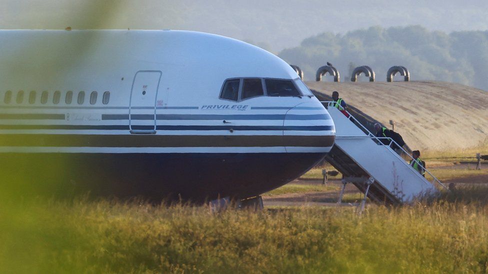 Officials board a plane that was due to take people to Rwanda in 2022