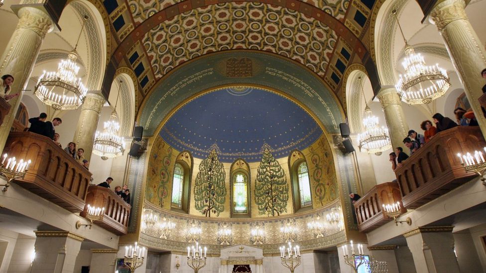 The interior of the Moscow Choral Synagogue shows a magnificent domed ceiling lit with candles and elaborately decorated.