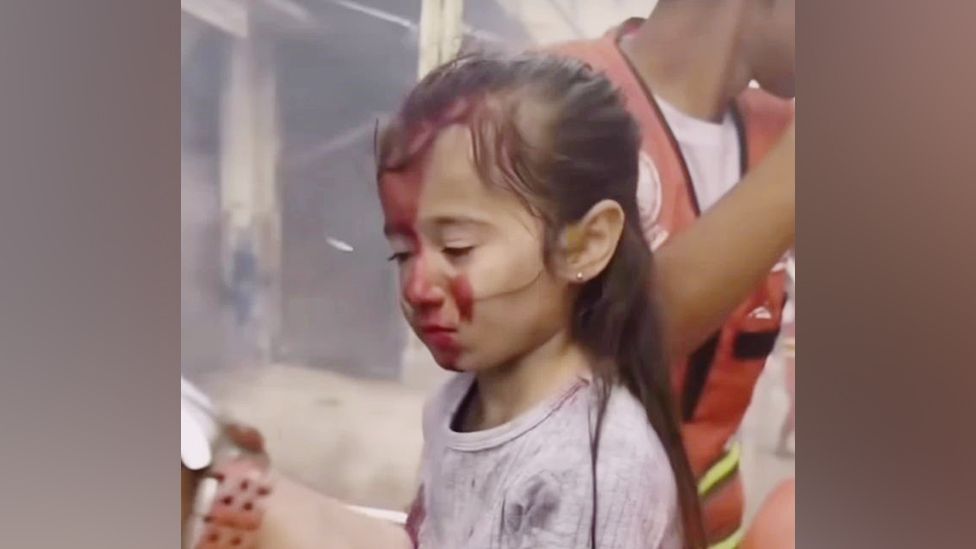 A still from behind-the-scenes footage of a short film, showing a girl with stage blood on her face being attended to by parademics