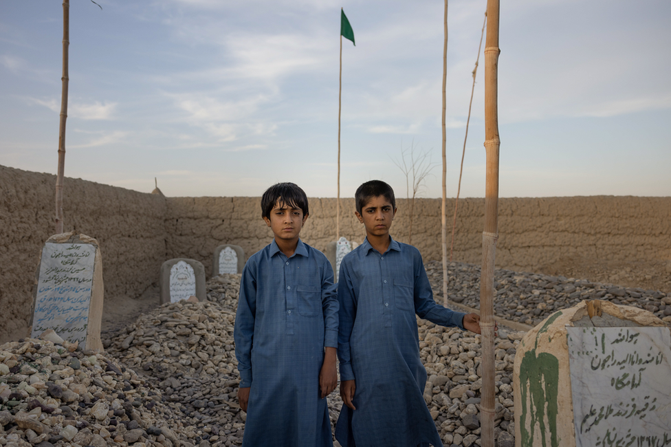 Bilal and Imran Uzbakzai by their mother's grave. They were too young when she died to remember her now. Image: Julian Busch/BBC
