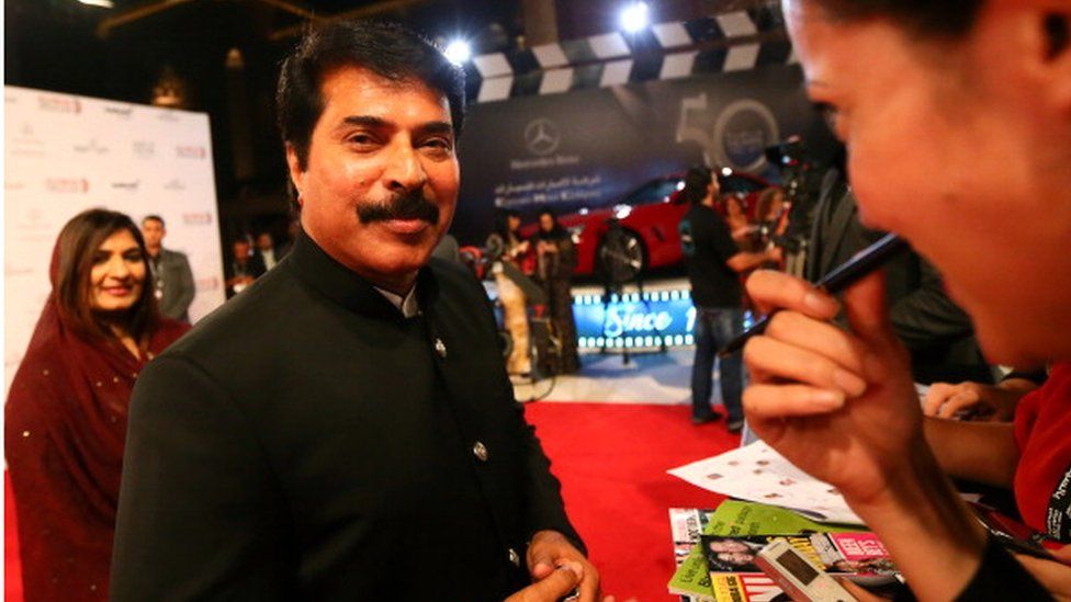 Indian Bollywood actor Mammootty (C) speaks with journalists as he arrives with his wife (L) at the opening ceremony of the Abu Dhabi Film Festival (ADFF) on October 11, 2012