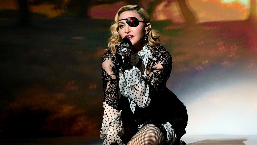 Madonna kneeling as she sings during a live show