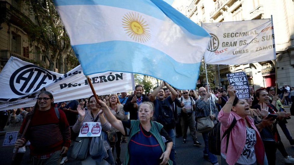 A middle-aged woman waves a large Argentinian flag during a protest against university cuts in Buenos Aires.