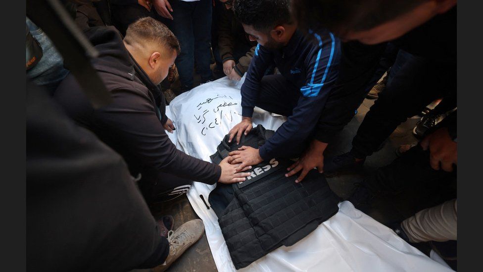 Fellow journalists mourn over the body of Mustafa Thuraya after he was killed in an Israeli air strike, at his funeral in Rafah, in the Gaza Strip (7 January 2024)