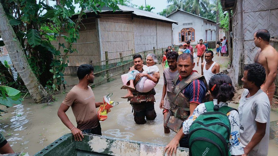 Residents in Assam walk through flooded roads