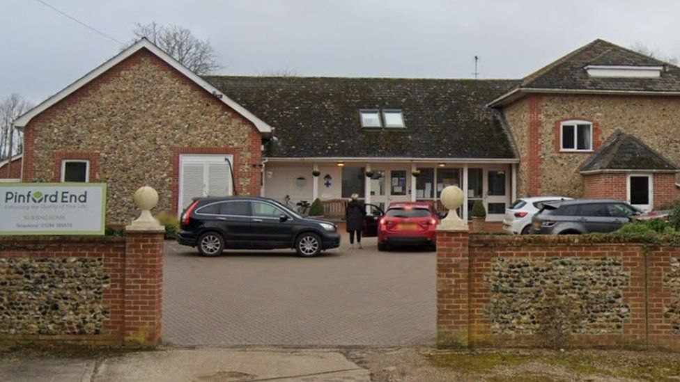 Brick-built care home with two 2-storey wings connected by single-storey glazed corridor.