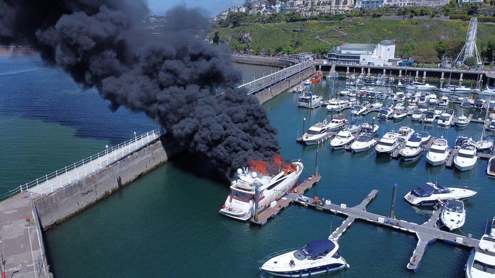 Thick black smoke rises from a fire on a yacht at Torquay harbour