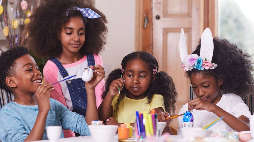 kids sitting together painting easter eggs