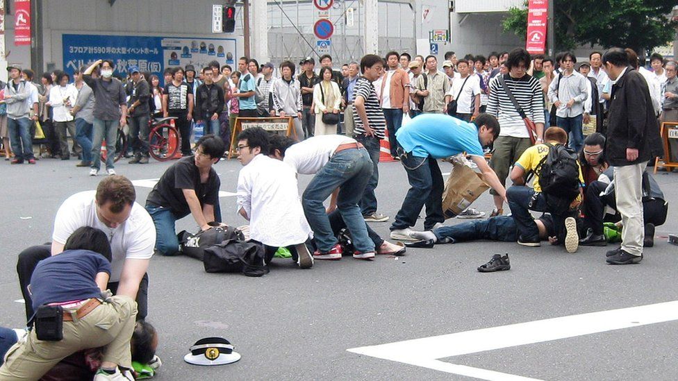 People attend injured victims lying on the road after they stabbed in the attack at Tokyo's Akihabara electronics shops district on June 8, 2008