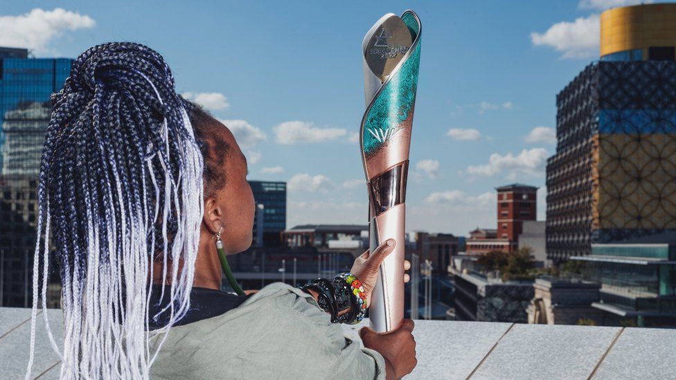 Artist Laura Nyahuye holding the baton she designed