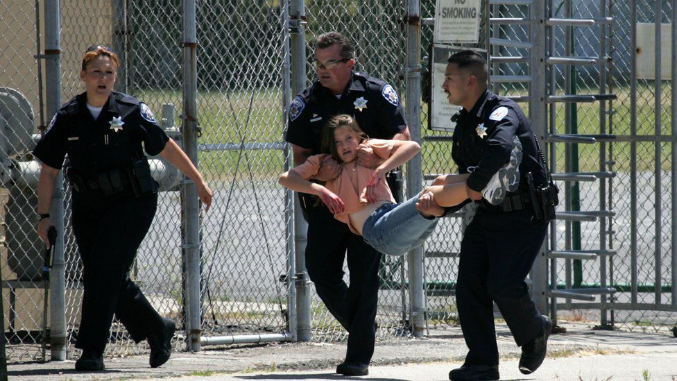 A school student being carried by two police officers during an active-shooter drill