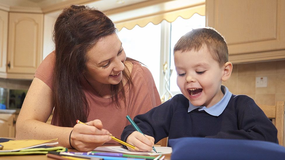 A mother and young son doing homework in a kitchen