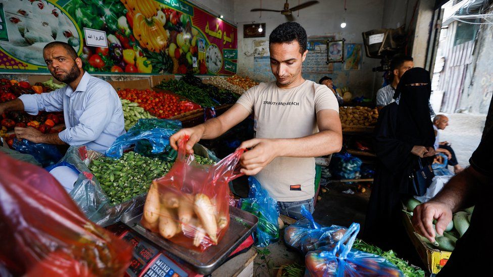 A Palestinian weighs vegetables in a shop, as a ceasefire holds, in Rafah in the southern Gaza Strip August 8, 2022.