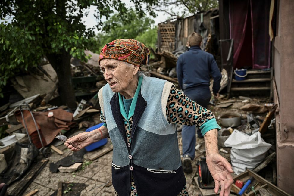 An elderly woman stands outside her heavily damaged house after it was hit by a missile in the city of Bakhmut in the eastern Ukrainian region of Donbas on 22 May 2022