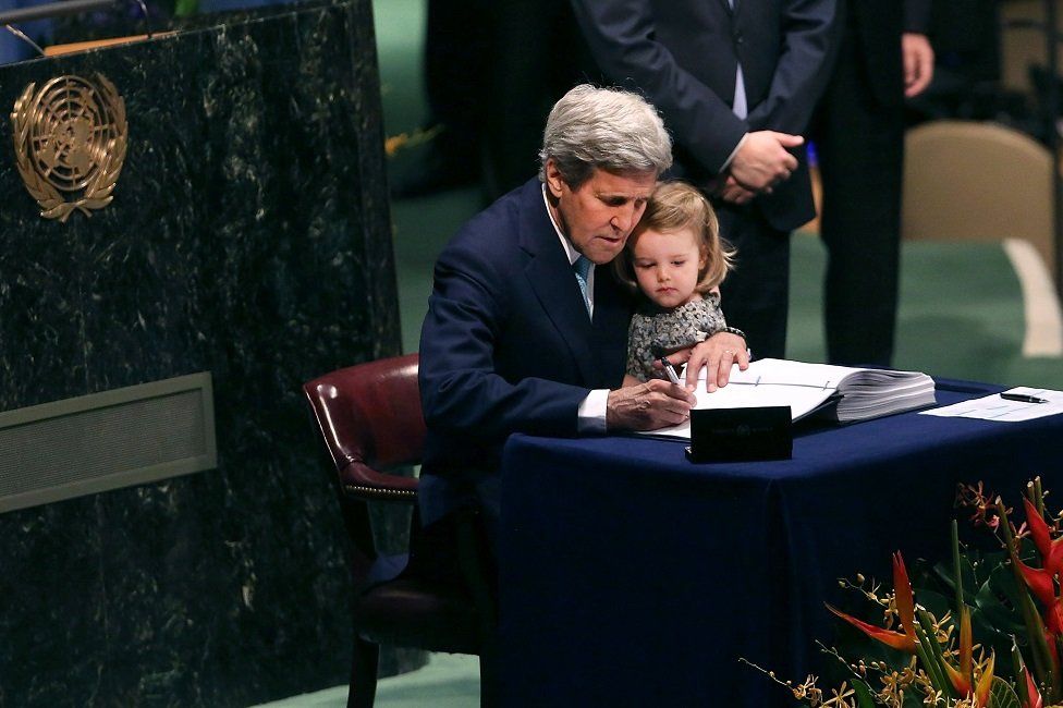 John Kerry is joined by his granddaughter as he signs the Paris climate agreement in 2016