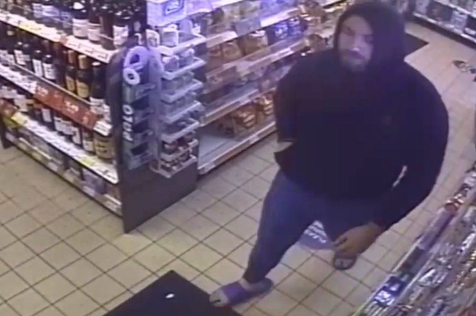 CCTV of a hooded man in a petrol station shop