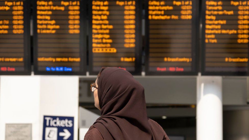 Passengers interact with timetables inside a quiet Grand Central / New Street station