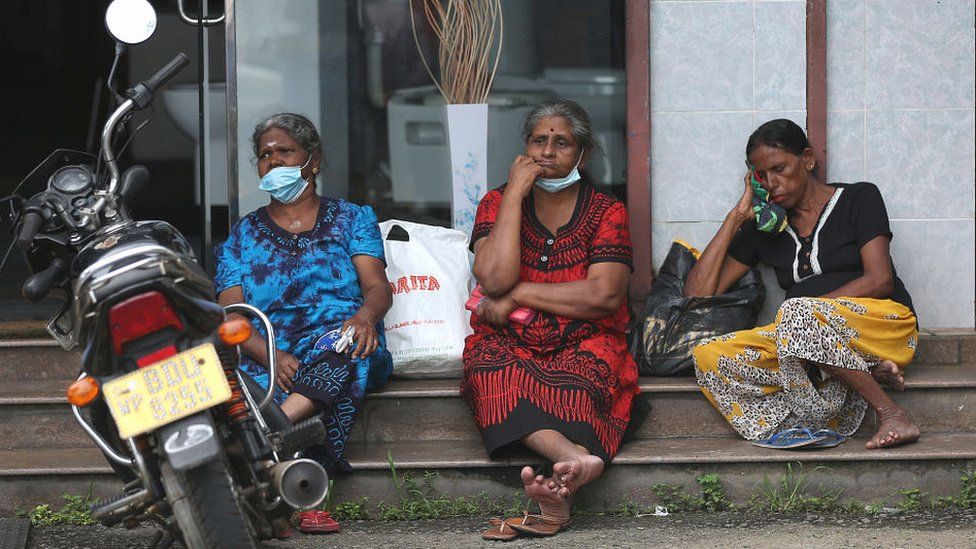 People wait to buy kerosene oil at a petrol station in Colombo.