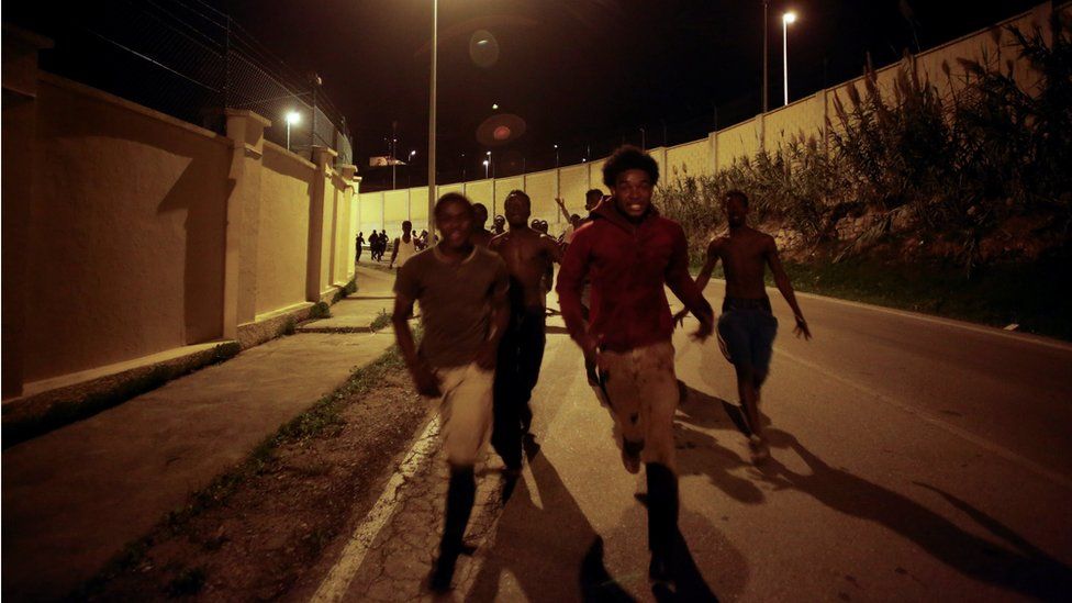 African migrants run on a road after crossing the border fence between Morocco and Spain"s north African enclave of Ceuta, December 9, 2016
