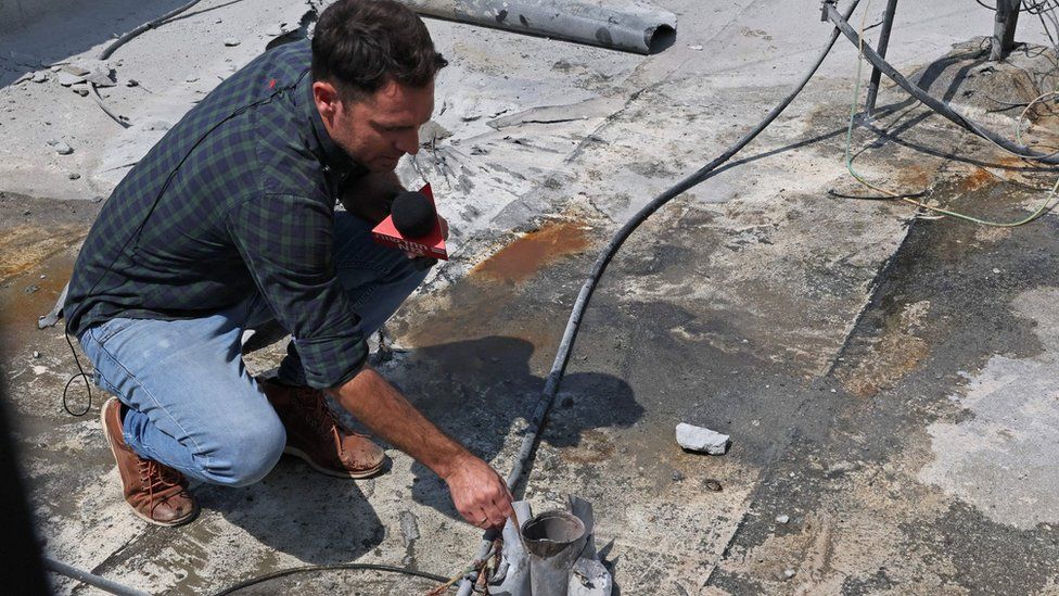 A reporter holds the remains of a rocket launched from the Gaza Strip, in the southern Israeli city of Sderot on August 6, 2022. -