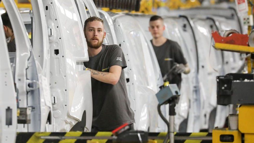 Factory employees work on a car assembly line at the Renault factory, in Maubeuge