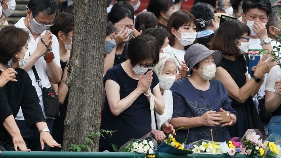 People pray and cry as a hearse with the body of Shinzo Abe drives past them in Tokyo, Japan. Photo: 12 July 2022