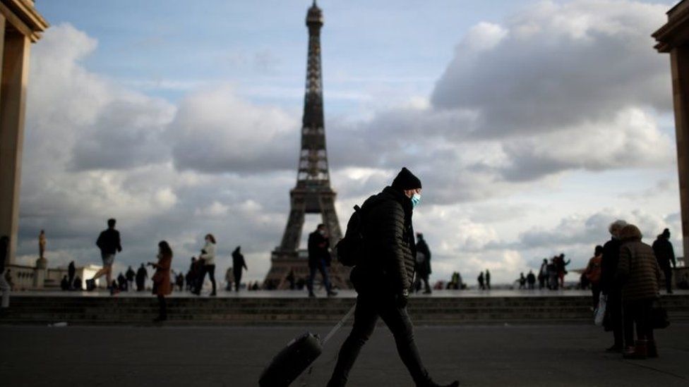 A man wearing a protective face mask walks at Trocadero square near the Eiffel Tower in Paris