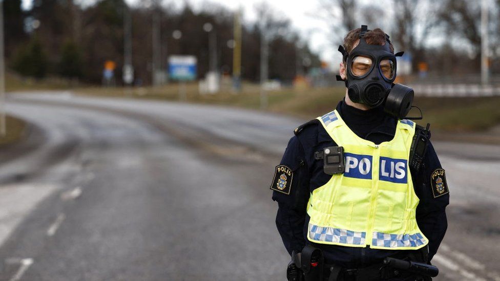 Police officer wearing gas mask standing at the scene after emergency services were called to Sweden's Security Service headquarters