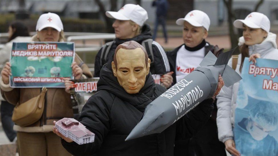 A man wearing a mask depicting Russian President Vladimir Putin commemorates the second anniversary of the shelling of the Mariupol Drama Theatre where more 300 civilians were killed