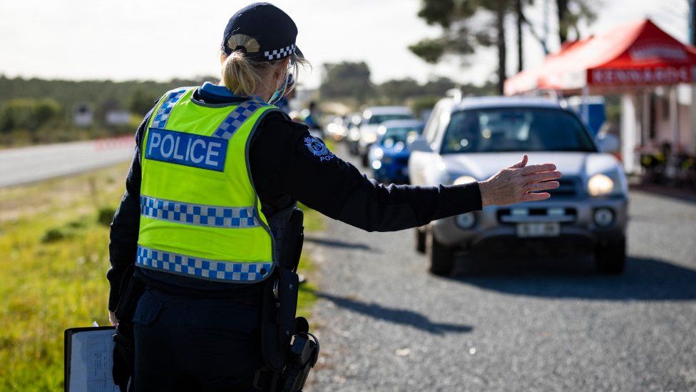 A member of the police force inspects cars at a Border Check Point on Indian Ocean Drive, north of Perth on June 29, 2021