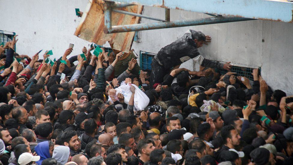 Crowds of Palestinians try to collect aid at an UNRWA warehouse in Gaza City (18 March 2024)
