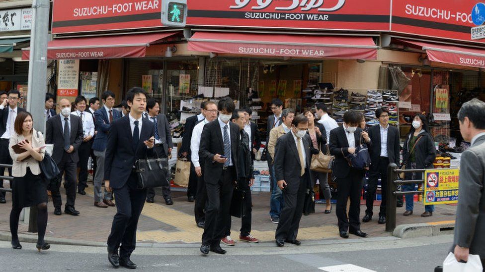 Men and women in business attire cross a street on March 20, 2015 in Tokyo, Japan.