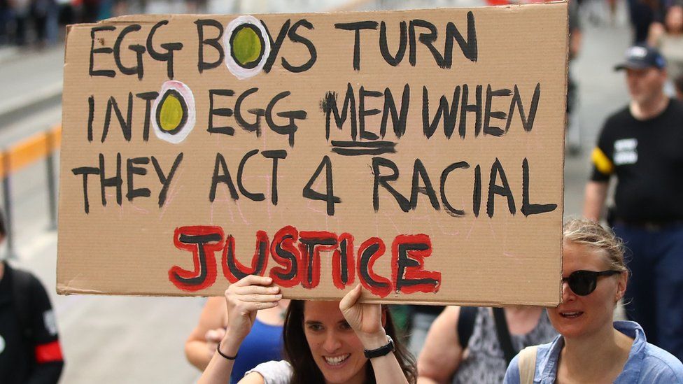 A protester in Melbourne holds a placard reading: "Egg Boys turn into egg men when they act 4 racial injustice"