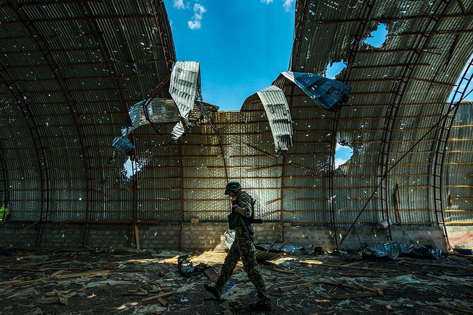 A Ukrainian soldier walks inside a barn destroyed by Russian shelling near the frontline of the Zaporizhzhia province