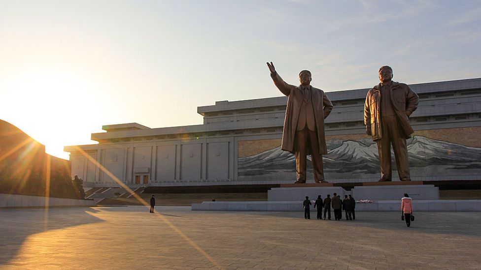 North Koreans pay their respects at the bronze statues of late North Korean leaders Kim Il Sung and Kim Jong Il